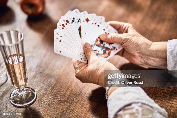 close-up of senior woman at table with champagne glass playing cards - senior women wine stock pictures, royalty-free photos & images