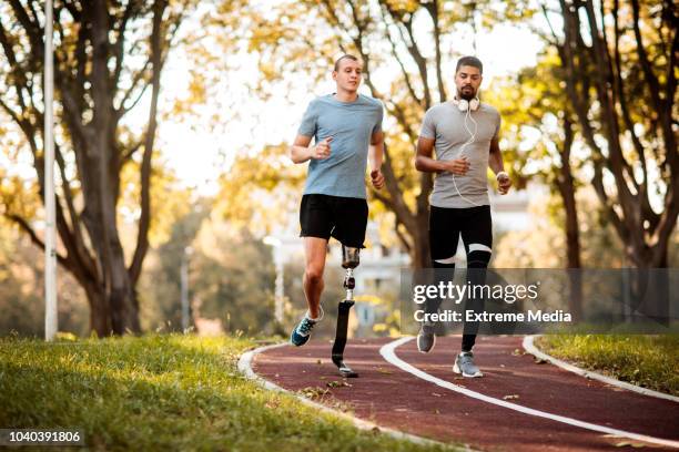 vrienden joggen buiten - gehandicapte atleet stockfoto's en -beelden