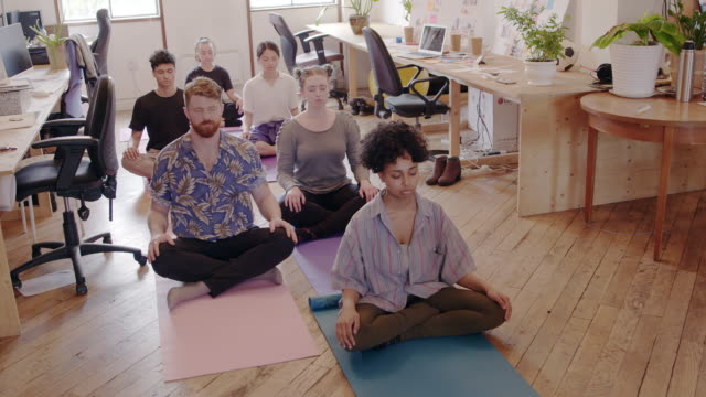 Serene creative business people meditating in office