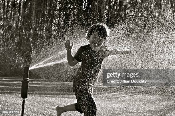 boy in sprinkler - jillian stock pictures, royalty-free photos & images