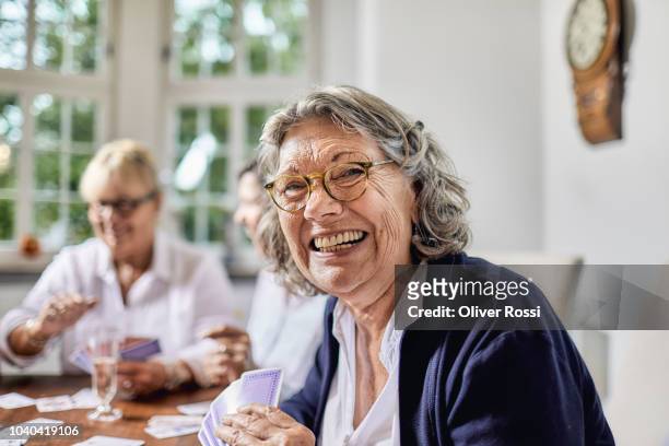 portrait of happy senior woman playing cards with her friends - retirement card stock pictures, royalty-free photos & images