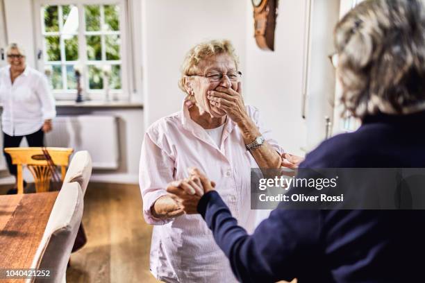 happy senior friends facing each other - mano tapando la boca fotografías e imágenes de stock