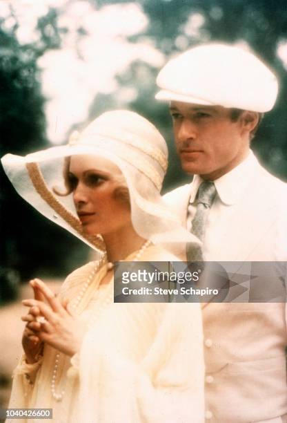 View of American actors Mia Farrow and Robert Redford, both in white attire, outdoors in a scene from the film 'The Great Gatsby' , Newport, Rhode...