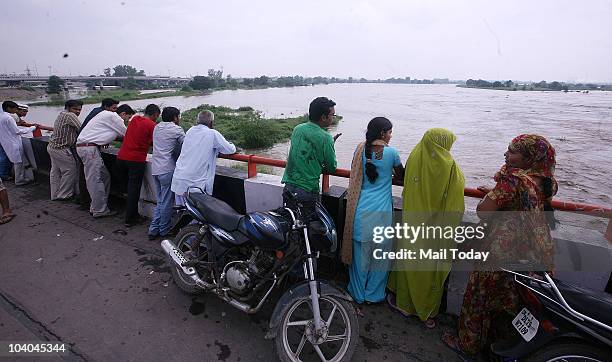 People watch the rising waters of the Yamuna river at the Geeta Colony in New Delhi on September 11, 2010.