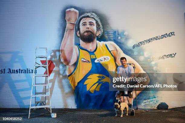 One of the two artists Jacob Butler poses with Banjo the French Bulldog in front his Josh Kennedy 2018 Mural commissioned by Seven West Media and the...