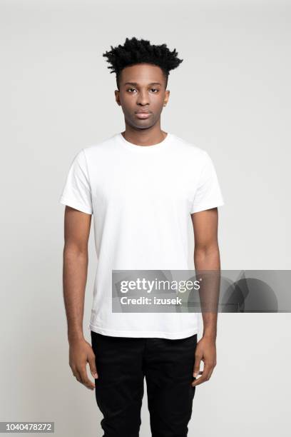 ernster junge afro amerikanische mann stehend im studio - white/black shirt stock-fotos und bilder