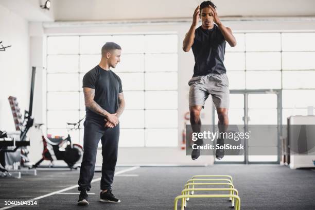 dehnung in der turnhalle mit einem personal trainer - athlet stock-fotos und bilder