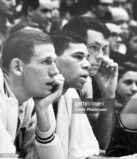 View of, from left, American basketball players Jeff Mullins, Willie Jones, and Bill Bradley as they sit on the sidelines during the elimination...