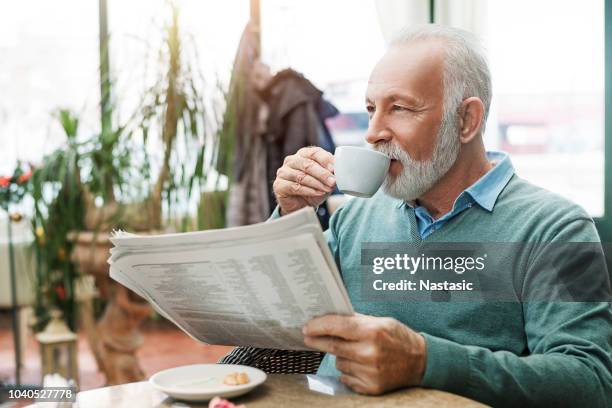 uomo anziano con giornale che beve caffè - coffee and news paper foto e immagini stock