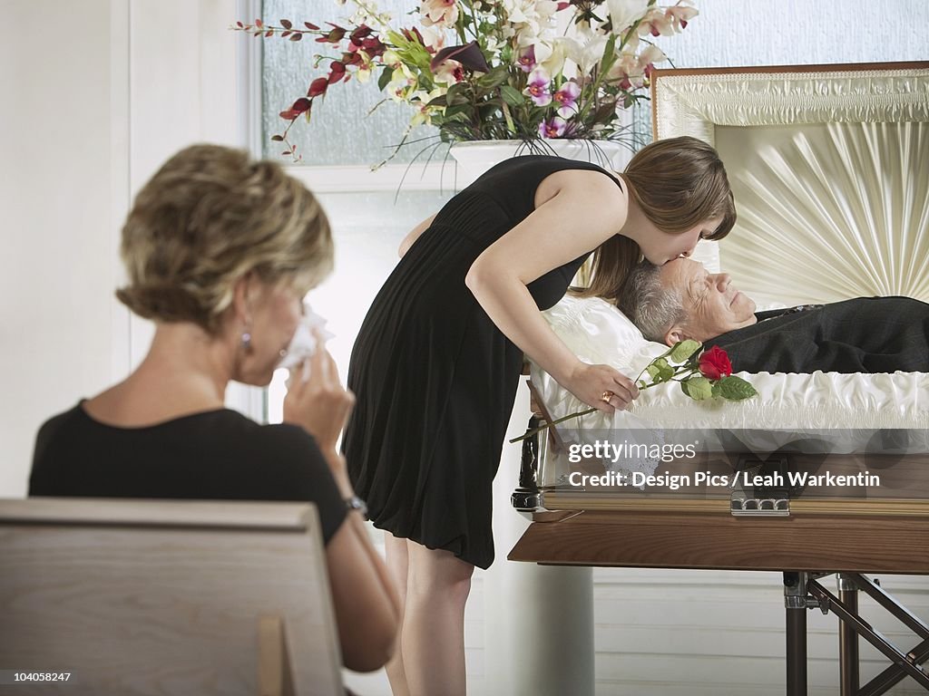 A Young Woman Kissing A Loved One In A Coffin At A Funeral