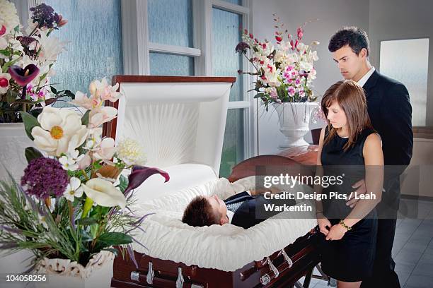 a young couple views a deceased loved one in a coffin - dead person stock-fotos und bilder