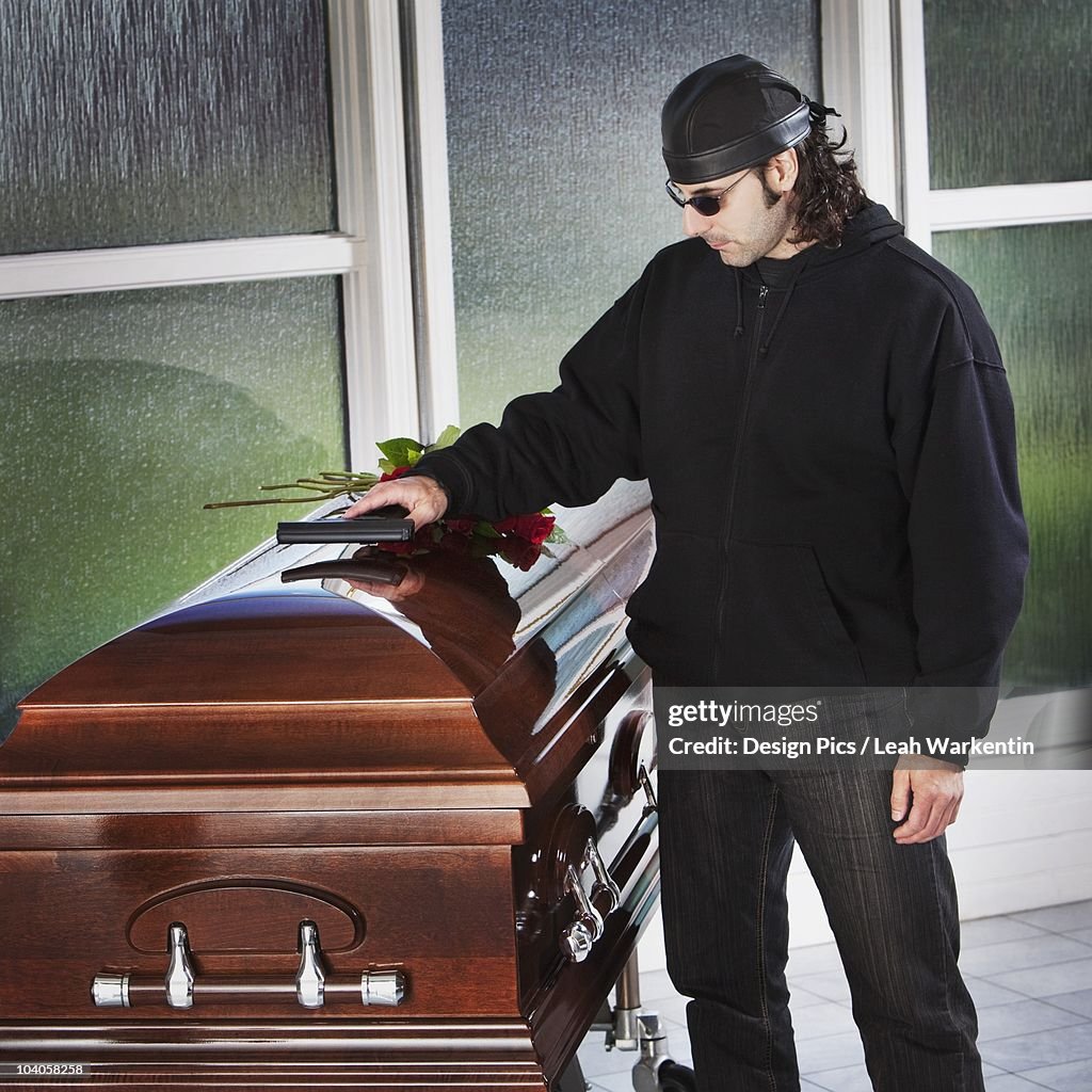 A Man Laying His Gun On Top Of A Coffin