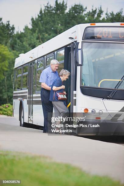 a senior couple getting on the city bus - alter mensch bushaltestelle stock-fotos und bilder