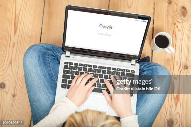 Eine Frau sitzt auf dem Boden und ist mit ihrem Laptop auf der Startseite von Google.