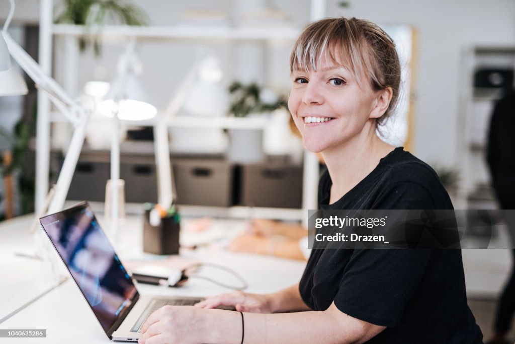 Ritratto di grafico in Scandinavia, che lavora su laptop.