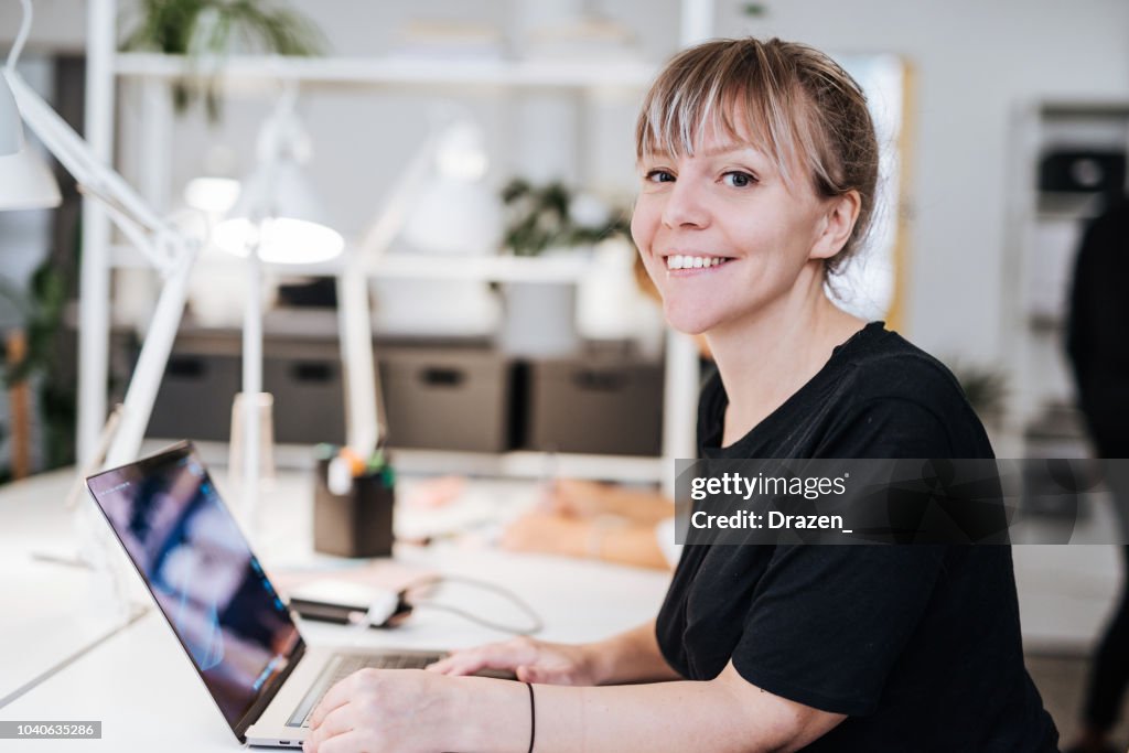 Portrait of graphic designer in Scandinavia, working on laptop.