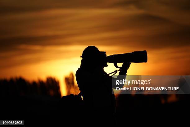 Photographer works at sunrise ahead of a practice session ahead of the 42nd Ryder Cup at Le Golf National Course at Saint-Quentin-en-Yvelines,...