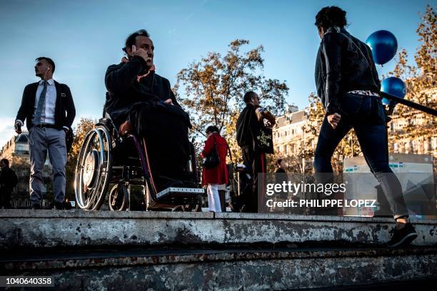 Man sits in his wheelchair on top of the stairs of a metro station in Paris on September 26, 2018 during a demonstration called by the Paralysed...