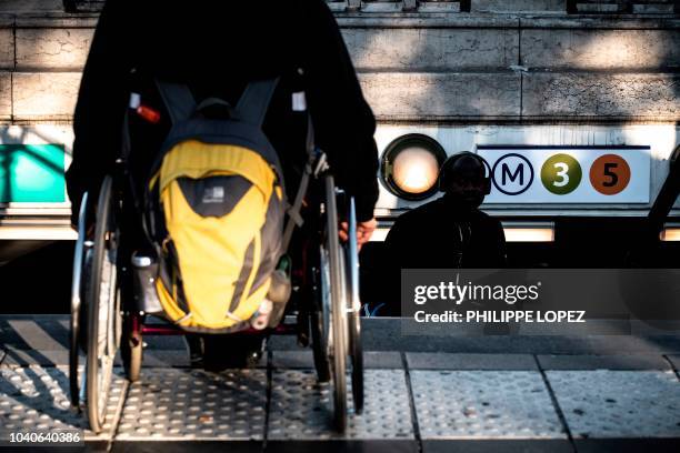 Man sits in his wheelchair on top of the stairs of a metro station in Paris on September 26, 2018 during a demonstration called by the Paralysed...