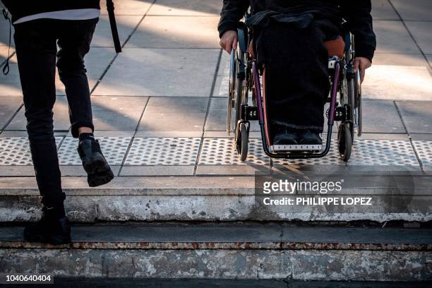 Man sits in his wheelchair on top of the stairs of a metro station in Paris on September 26, 2018 during a demonstration called by the Paralysed...