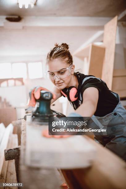 schattig vrouwtje leren hoe een houten plank zand - timmerman stockfoto's en -beelden