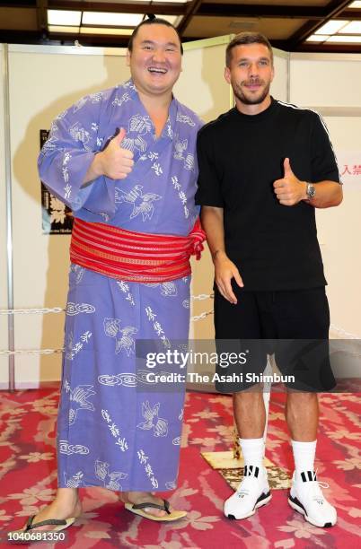 Mongolian yokozuna Hakuho and Lukas Podolski of Vissel Kobe pose for photographs on day eleven of the Grand Sumo Autumn Tournament at Ryogoku...