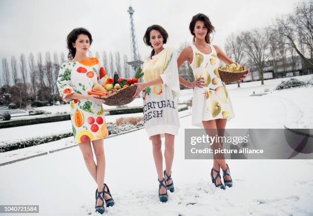 Three models of Portugal, the 'Fruit Logistica 2015' partner country, pose in front of fruit and vegetable baskets in the snow covered summer garden...