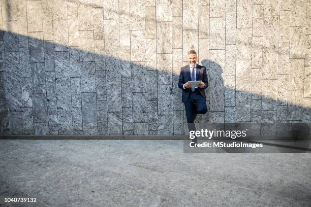 smiling businessman using digital tablet - men's formalwear stock pictures, royalty-free photos & images