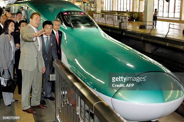 Standing by a bullet trains California Governor Arnold Schwarzenegger gestures as he listens to Masaki Ogata , vice president of East Japan Railway...