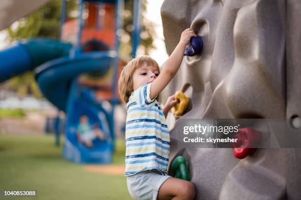 little boy clambering up the wall on the playground. - child climbing stock pictures, royalty-free photos & images