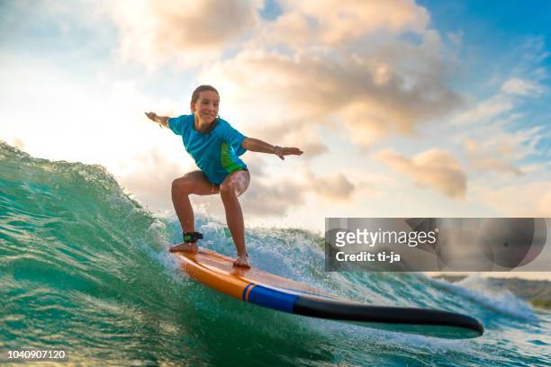 jong meisje surfen bij zonsondergang - female golf stockfoto's en -beelden