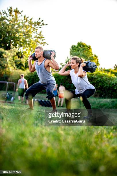 jonge man en vrouw samen buiten oefenen met gewichten - crossfit stockfoto's en -beelden