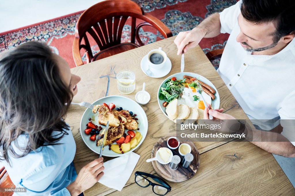 Fröhliches paar Frühstücken im Café und im Gespräch. Personen gemeinsam Essen