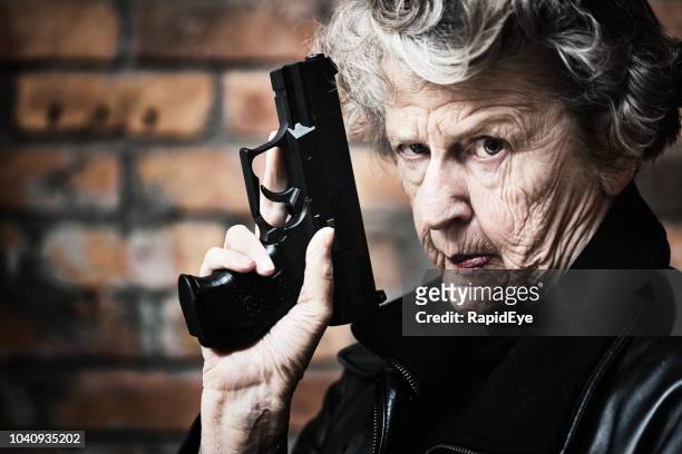 granny get your gun! fierce old woman holds pistol - female gangster stock pictures, royalty-free photos & images
