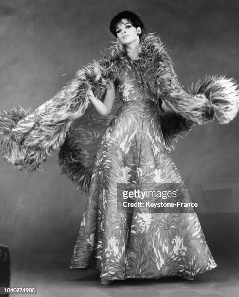 Mannequin portant un modèle Jeanne Lanvin : une robe du soir en mousseline imprimée mauve, bleu, vert et blanc, accompagnée d'un immense châle bordé...