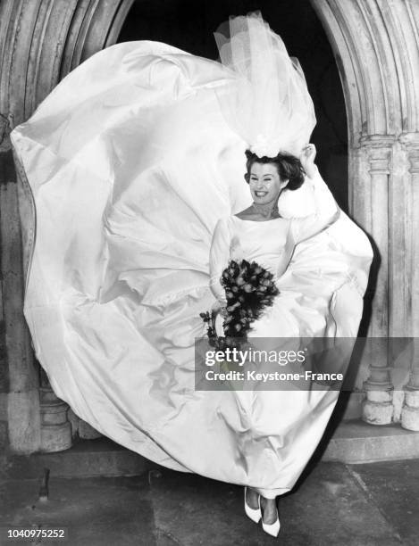 June Cooper, mariée sortant de l'église, voit sa robe et son voile se soulever dans le vent, à Londres, Royaume-Uni, le 9 décembre 1962.