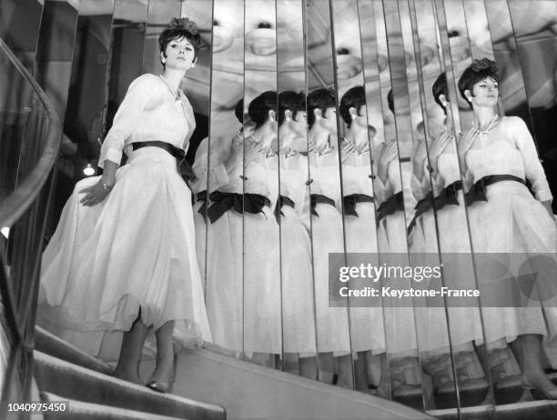 Mannequin présentant un modèle Chanel de la Collection Printemps/Eté 1963 : une robe du soir en organdi blanc avec une ceinture rouge, en France, le...