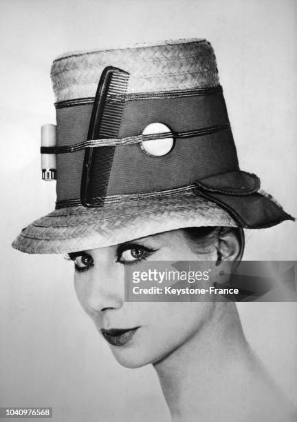Un modèle porte un chapeau insolite, dans lequel elle a coincé son peigne et un tube de rouge à lèvres, en France, circa 1960.