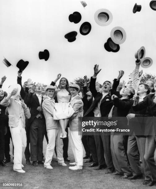 Les figurants venant du Wellington College jettent dans les airs leurs canotiers et haut-de-forme tandis que l'actrice Nancy Kwan portée est par deux...