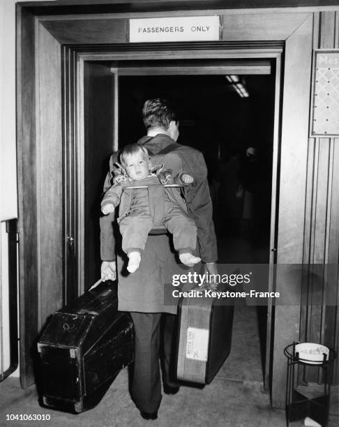 Monsieur Bonhoeffer, son fils âgé de 10 mois dans le dos et les mains chargées de valises, traverse la douane à l'aéroport pour se rendre à Hanovre...