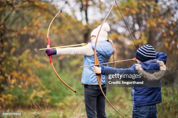 brother and sister playing archers in autumn forest - archery bow stock pictures, royalty-free photos & images