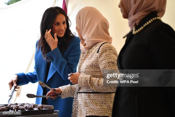 Meghan, Duchess of Sussex helps to prepare food at an event to mark the launch of a cookbook with recipes from a group of women affected by the...