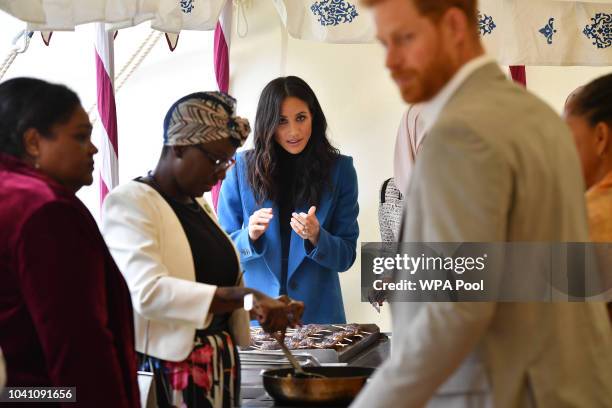 Meghan, Duchess of Sussex helps to prepare food at an event to mark the launch of a cookbook with recipes from a group of women affected by the...