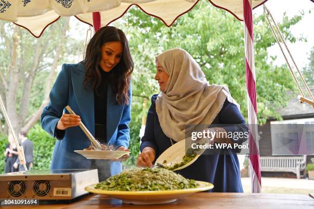 Meghan, Duchess of Sussex helps to prepare food at an event to mark the launch of a cookbook with recipes from a group of women affected by the...