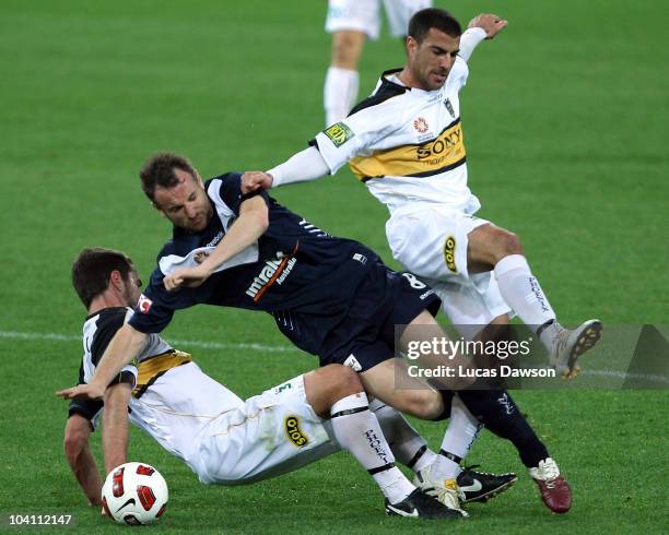 Grant Brebner of the Victory colllides with Emmanual Muscat and Tim Brown of the Phoneix during the round six A-League match between the Melbourne...