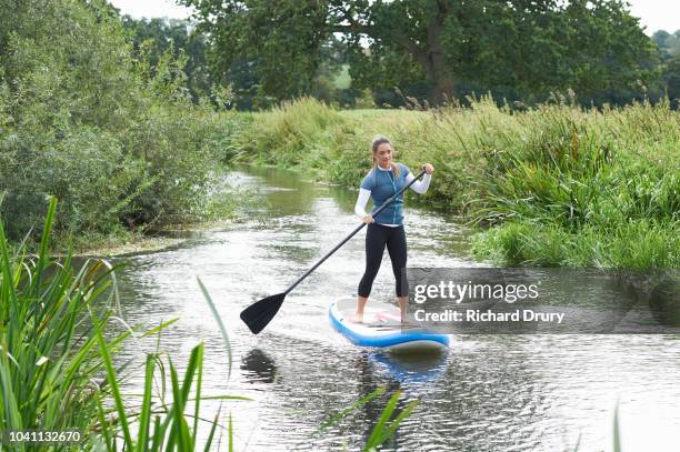 young woman paddleboarding on the river - paddleboard stock pictures, royalty-free photos & images