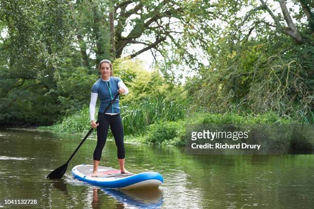 young woman paddleboarding on the river - paddle boarding bildbanksfoton och bilder