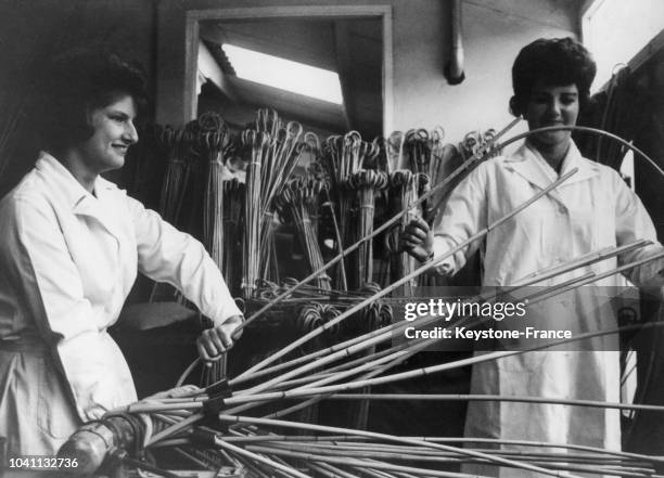 Deux employées testent la flexibilité des cannes en bambou fabriquées pour les punitions corporelles à l'école, le 30 juin 1965 au Royaume-Uni.