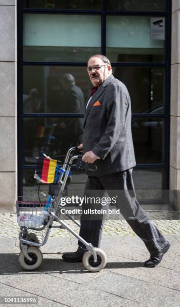 Germany Deutschland Berlin Ein Mann im Anzug geht mit seinem Rollator, an dem eine Deutschlandfahne befestigt ist, durch die Stadt.