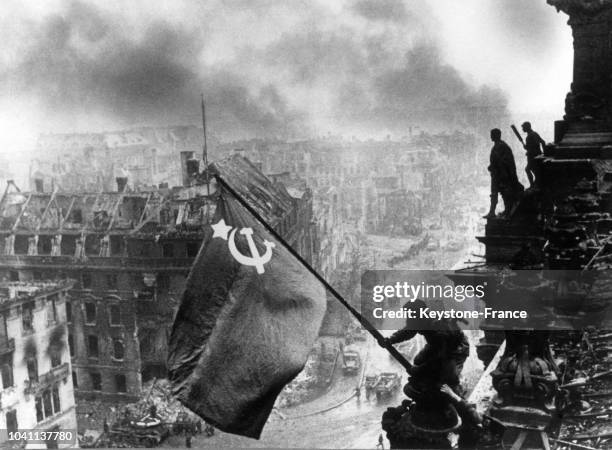 Un sergent russe Kovaliov, soutenu par son camarade, plante le drapeau russe sur le Reichstag tandis que Berlin brûle, le 2 mai 1945, en Allemagne.